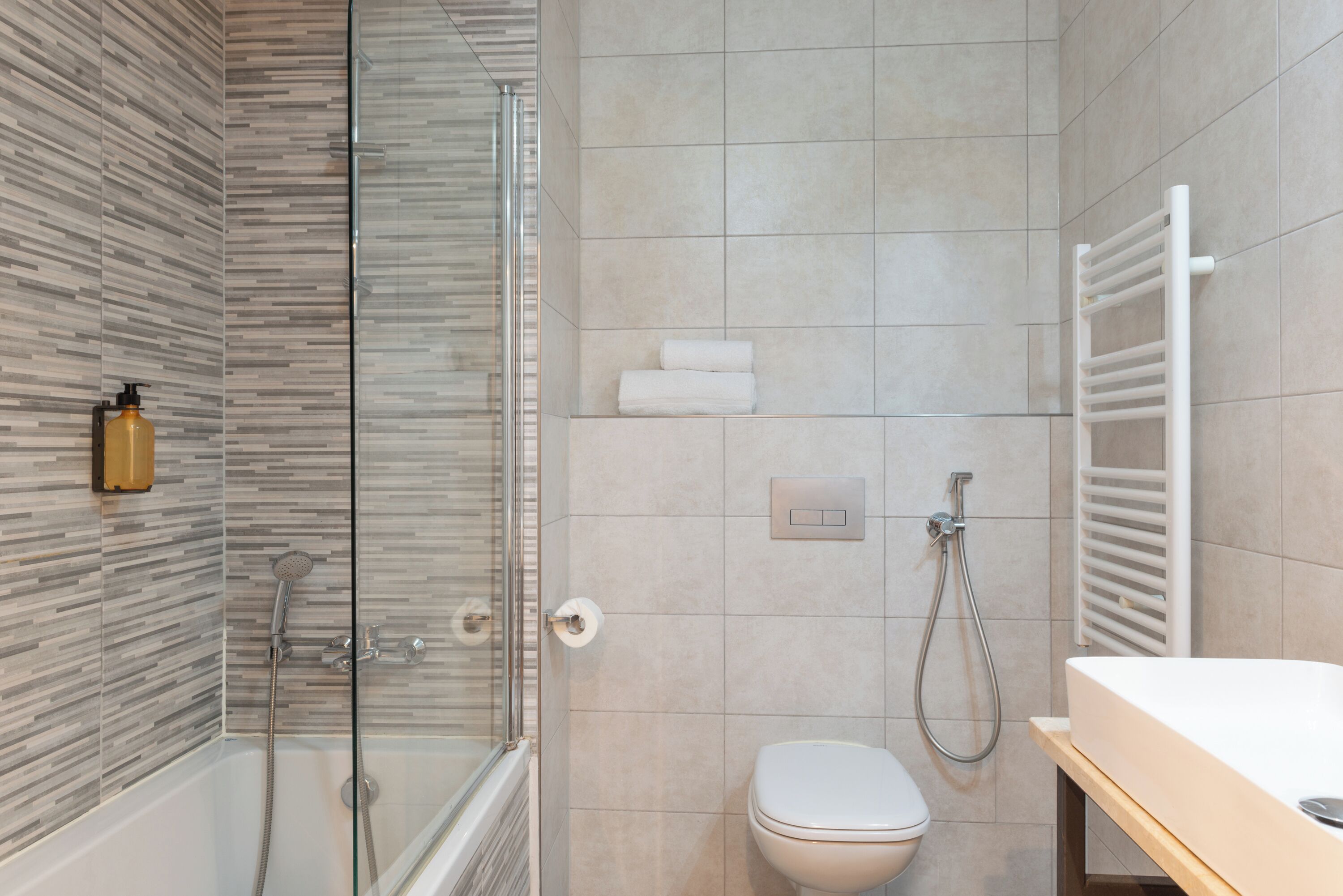 A modern bathroom with a glass shower enclosure, a toilet, and a sink.