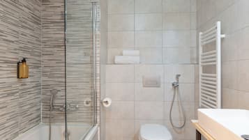 A modern bathroom with a glass shower enclosure, a toilet, and a sink.