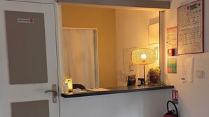 Un espace d’accueil comprenant un comptoir, un extincteur et une porte avec une pancarte.