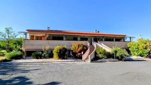 A two-story building with a red-tiled roof, a central staircase, and a parking lot. - HOTEL RESTAURANT MAS LE CHATELET (Saint-Paul-de-Fenouillet)