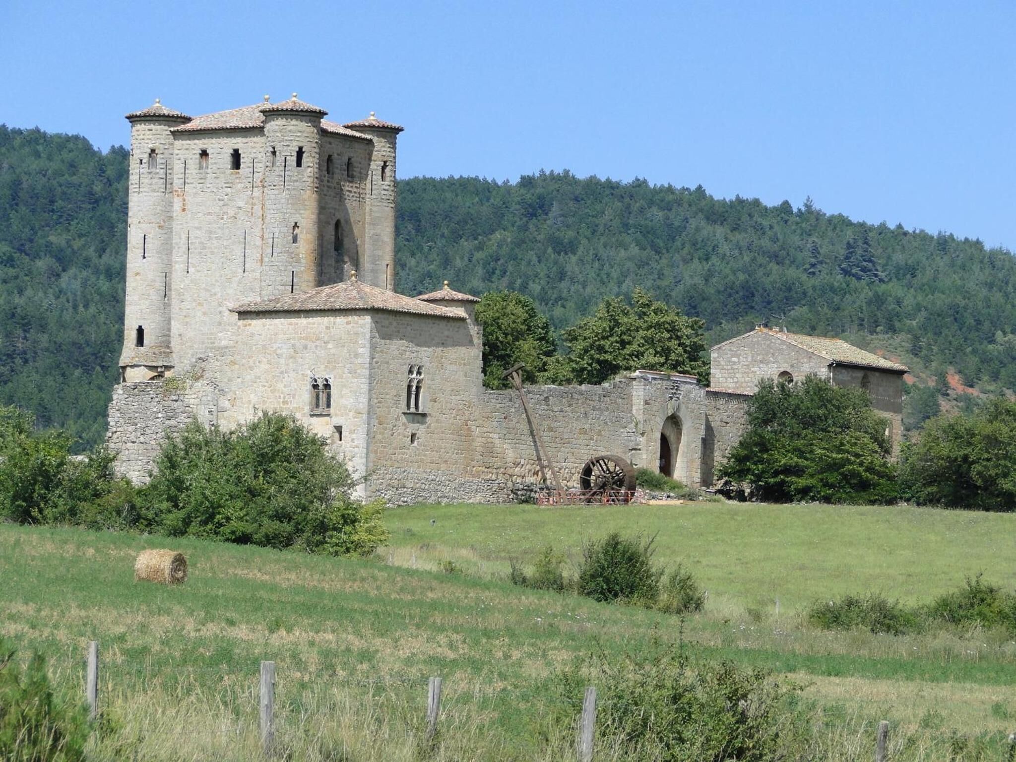 A historic stone building with a tower, arched windows, and a large water wheel.