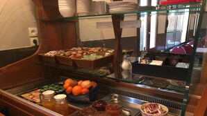 Un bufé con diversos alimentos, entre ellos frutas, pasteles y salsas.