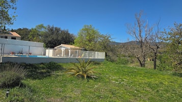 A residential property with a swimming pool, a fenced garden area, and a building with a tiled roof.