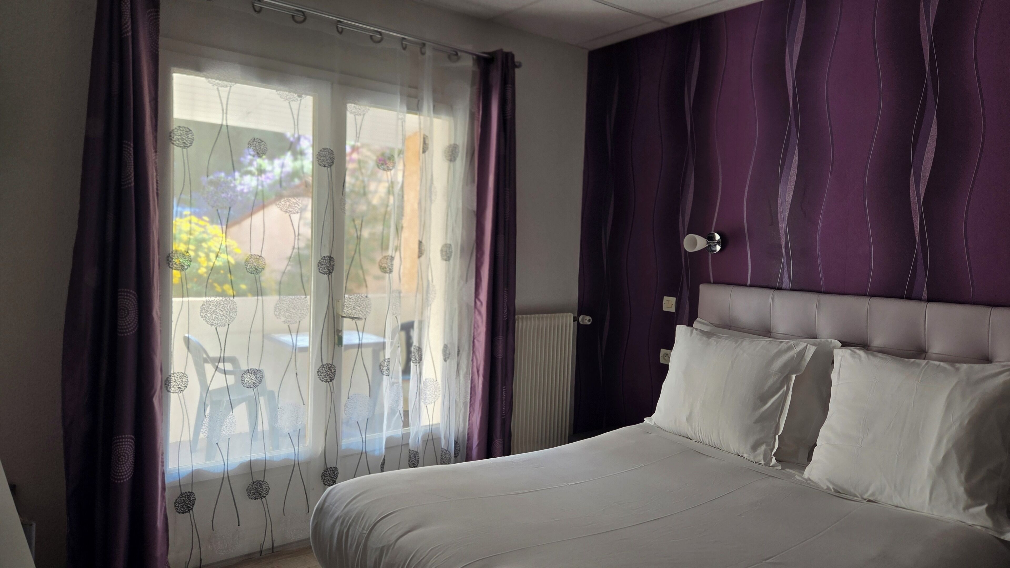 Ein Schlafzimmer mit Bett, Vorhängen und Blick ins Freie.