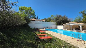 Une piscine avec des chaises longues et un espace salon abrité.
