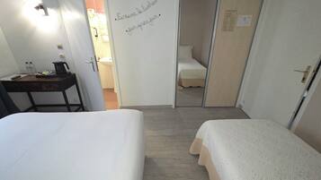 A hotel room with a bed, a desk with a lamp, and a door leading to a bathroom.