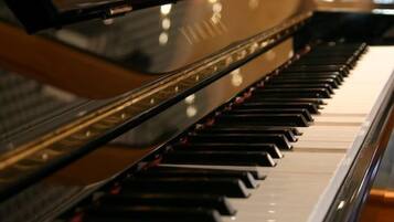 Un piano à queue doté d’une finition noire brillante et d’une surface réfléchissante.