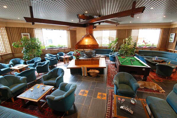 A spacious lounge area with multiple seating options, a pool table, and a fireplace.