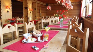 A wooden dining area with tables set for breakfast, including bread, eggs, and a beverage. - Hôtel Carlit (Font-Romeu-Odeillo-Via)