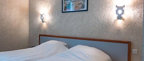 Un dormitorio con cama, mesita de noche y dos lámparas de pared.