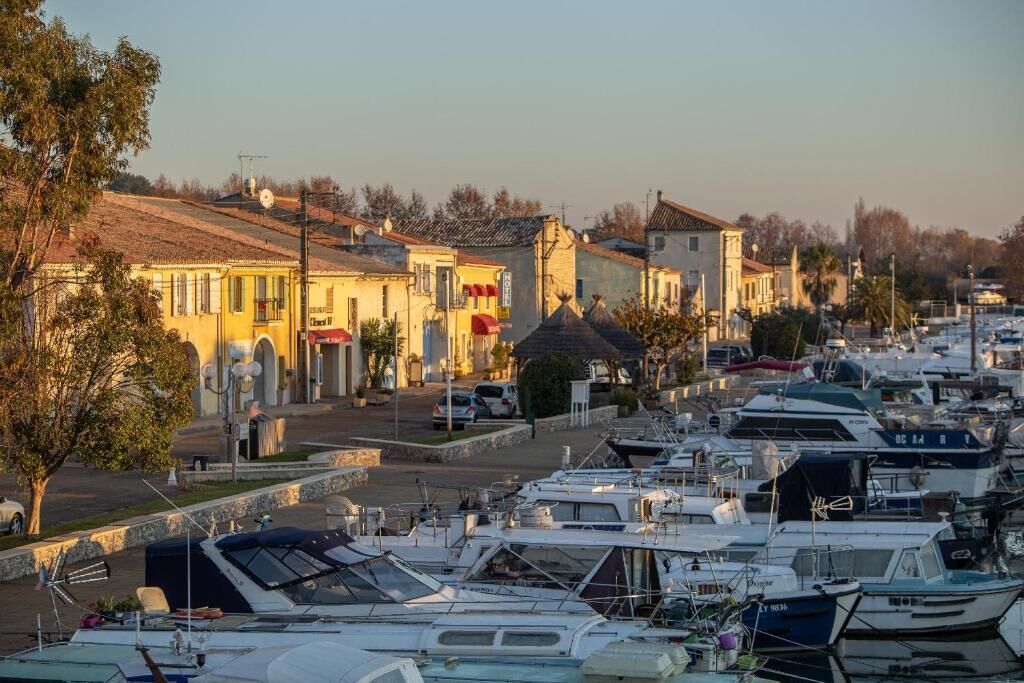 A marina with boats docked, buildings with traditional architecture, and a clear sky.