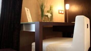 Una habitación de hotel moderna con una pared de acento de madera, un cuadro enmarcado, una mesita con un jarrón y una silla blanca.