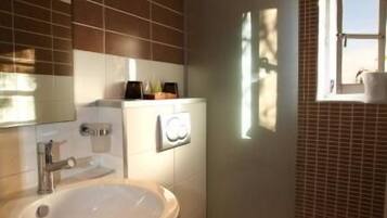 A bathroom with a white sink, a toilet, and a window.