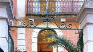 A building entrance with a wrought iron gate, a staircase, and potted plants. - Hôtel des Arceaux (Montpellier)