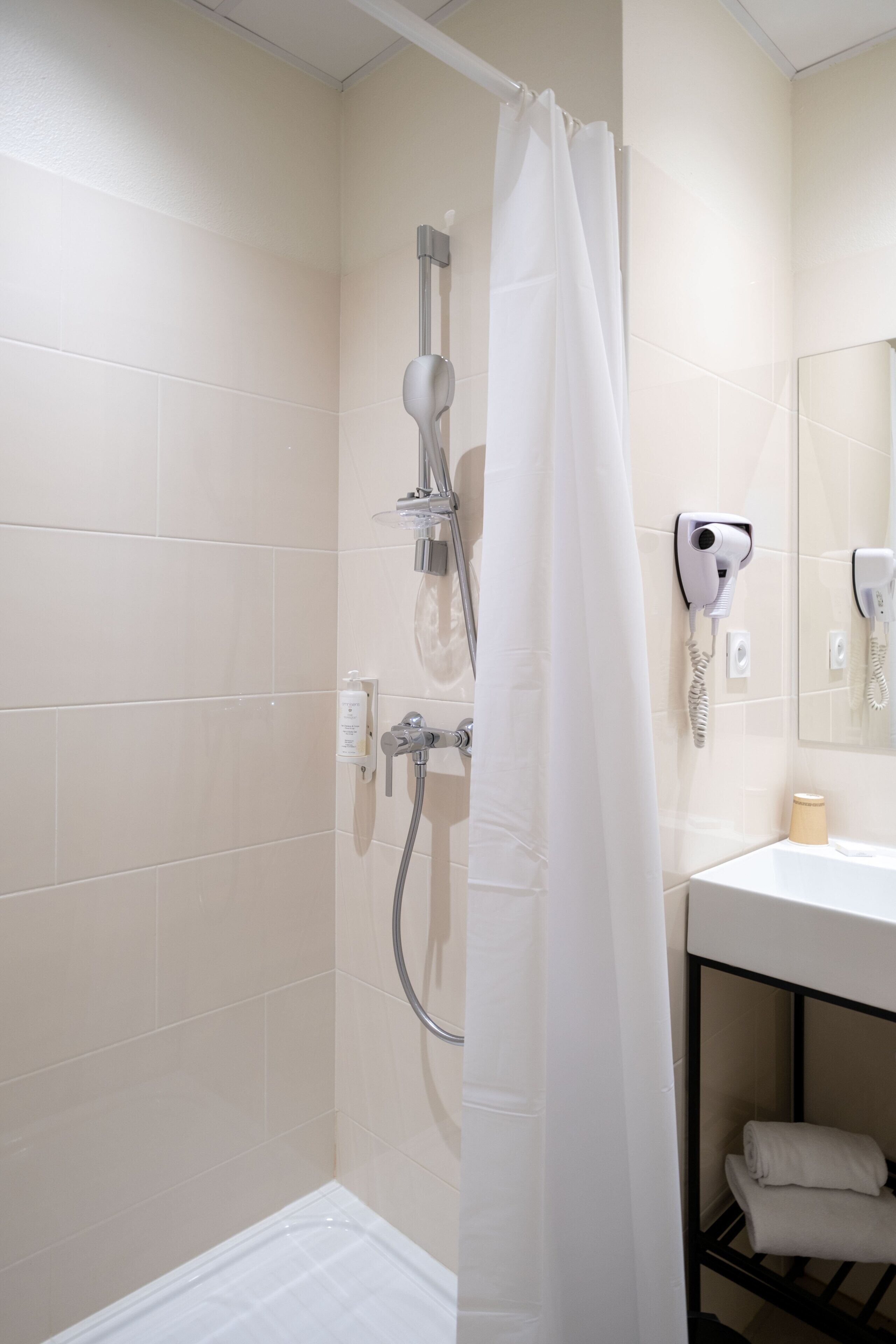 A bathroom with a shower, a toilet, a sink, and a towel rack.