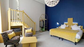 A bedroom with a bed, a chair, a small table, a staircase, and a wardrobe.