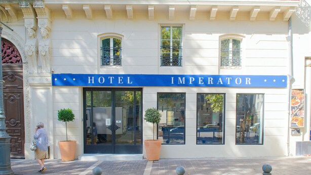 A hotel facade with a sign reading "HOTEL IMPERATOR," large windows, and two potted plants. - Hôtel Impérator (Béziers)
