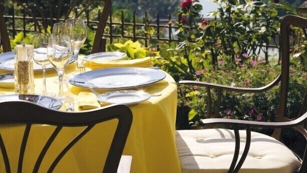 A dining table set outdoors with a view of a river and hills. - L'Esplanade (Domme)