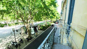 Un balcón con barandilla metálica que da a una calle con bicicletas estacionadas y un árbol.