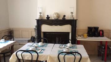 Un comedor con chimenea, mesas dispuestas con manteles blancos, sillas y una estación de café.