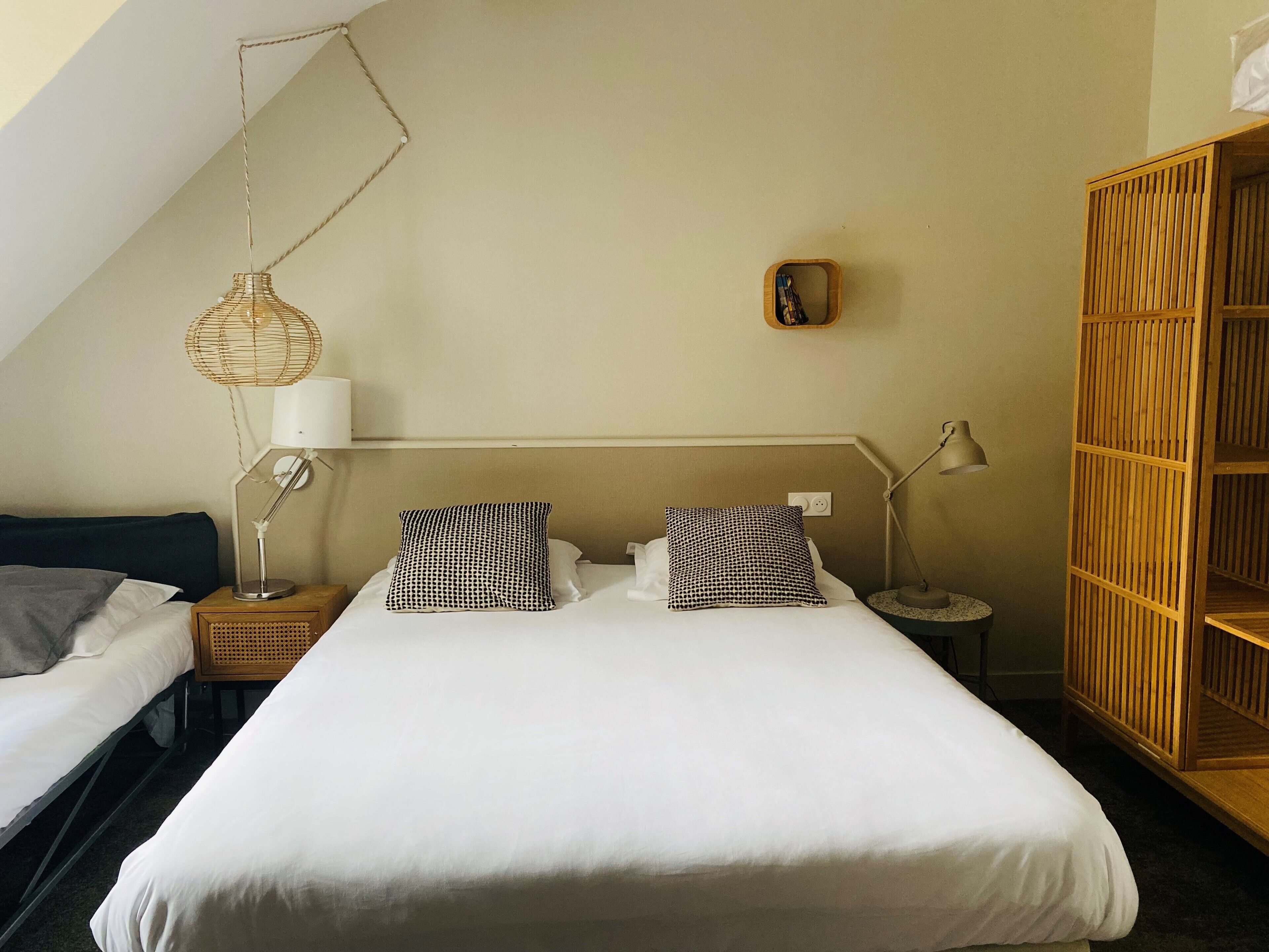 Ein Schlafzimmer mit einem großen Bett, zwei Nachttischen, einer Hängelampe und einem Holzschrank.