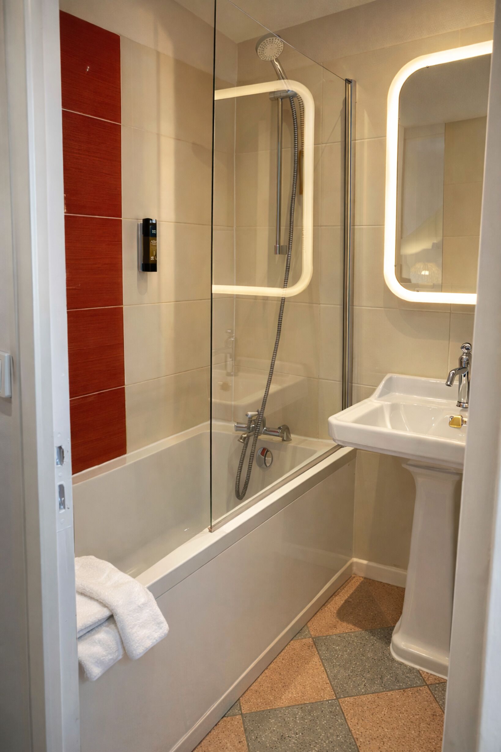 A modern bathroom with a glass-enclosed shower, a white sink, and a red accent wall.