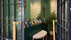Zona de recepción con un banco, una exhibición de libros y revistas, y una pared decorada con un mural.