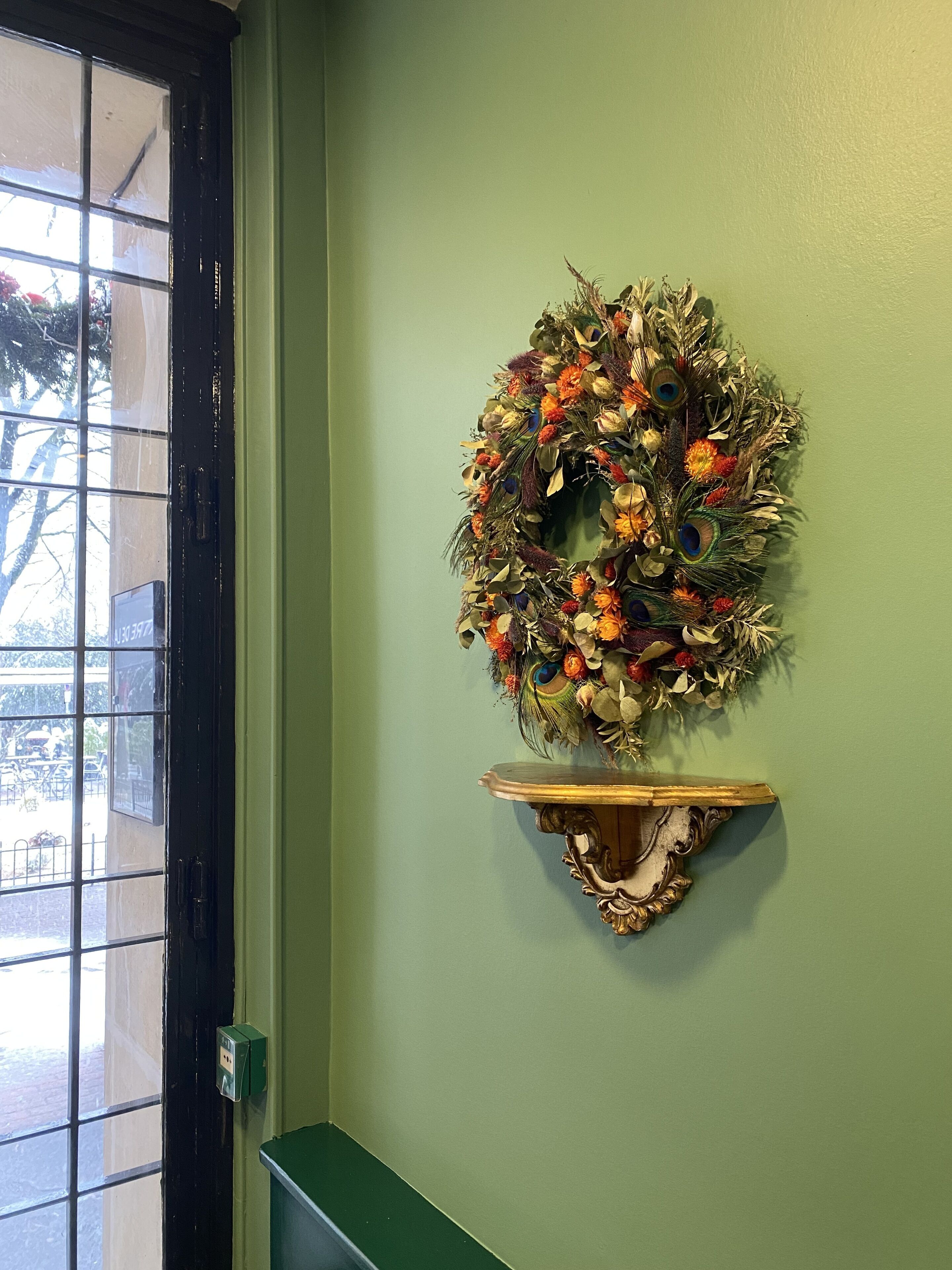 Une couronne décorative fixée au mur, avec une étagère placée en dessous.