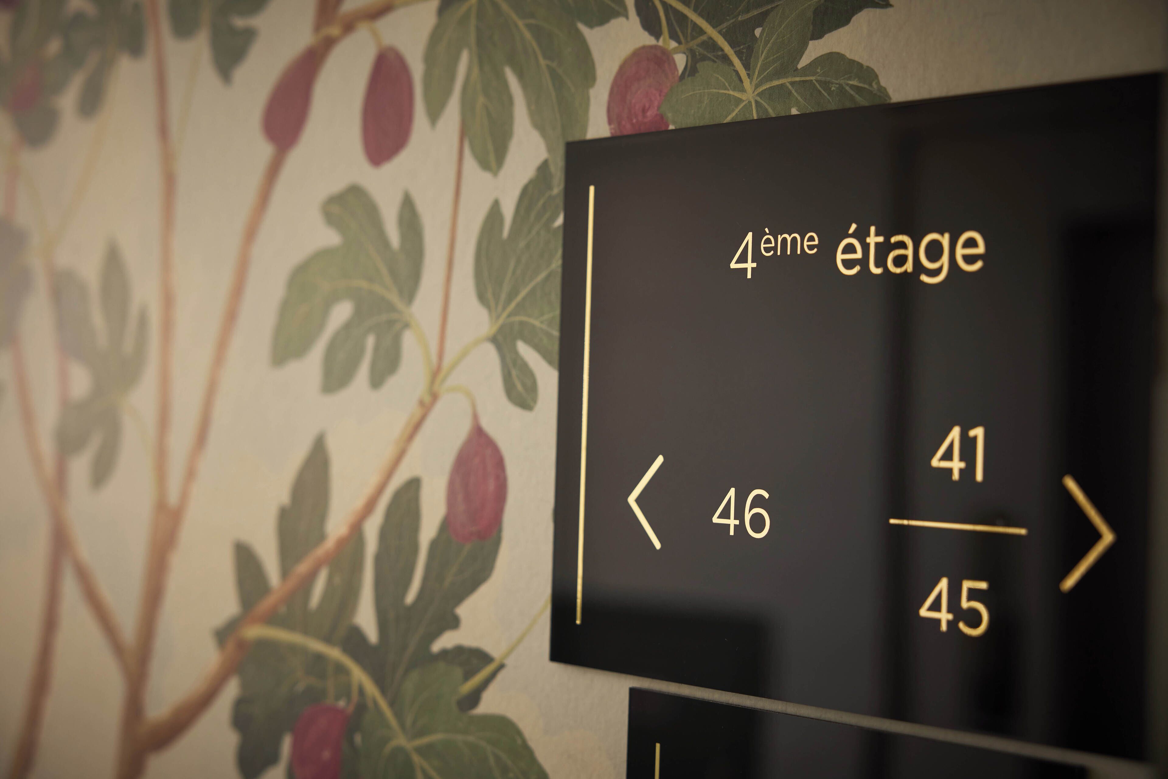 Una pared con un letrero que indica los números de las habitaciones y la frase francesa "4ème étage" (4to piso).
