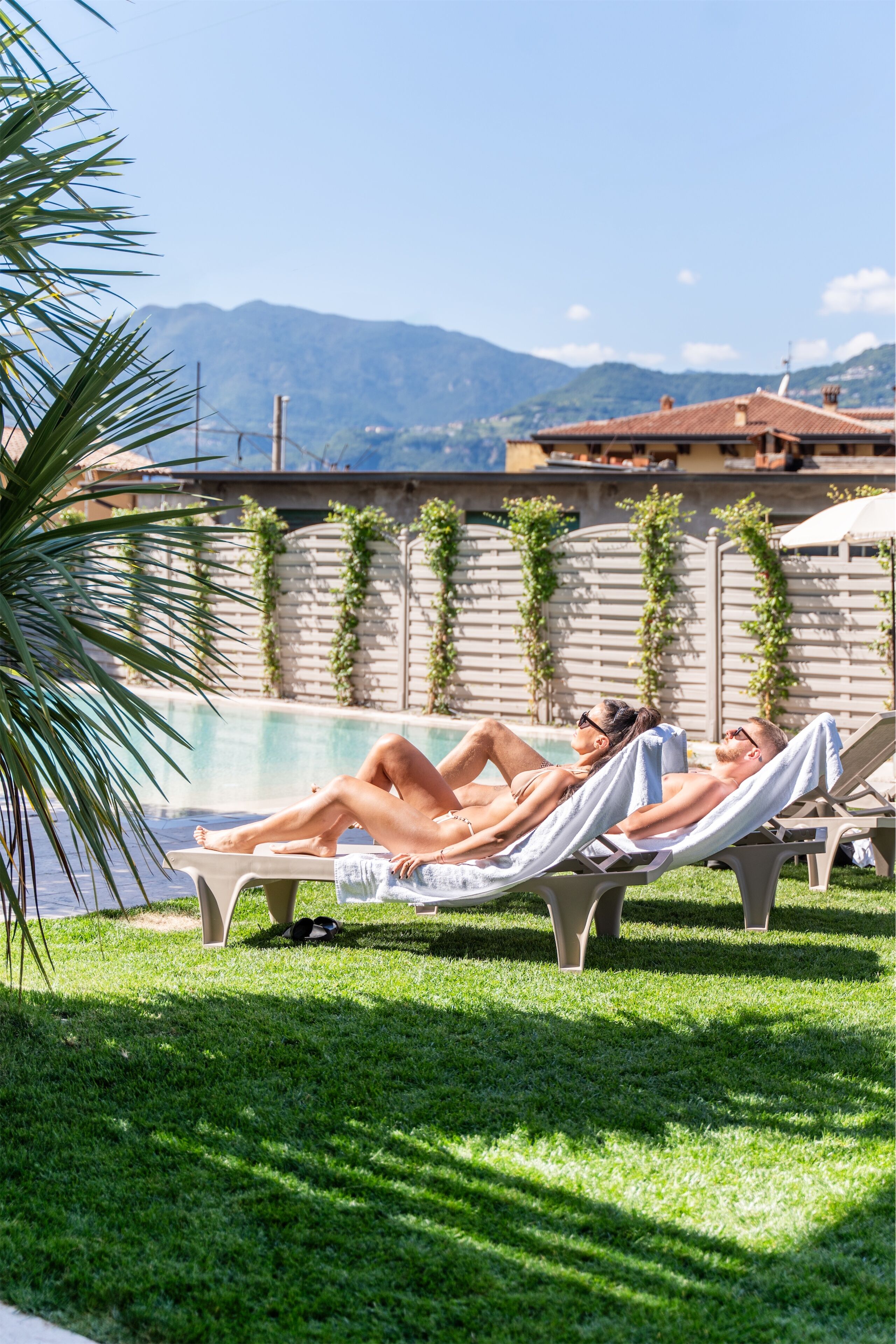Zona de piscina amb gandules i una piscina, envoltada de vegetació i un paisatge de muntanyes.