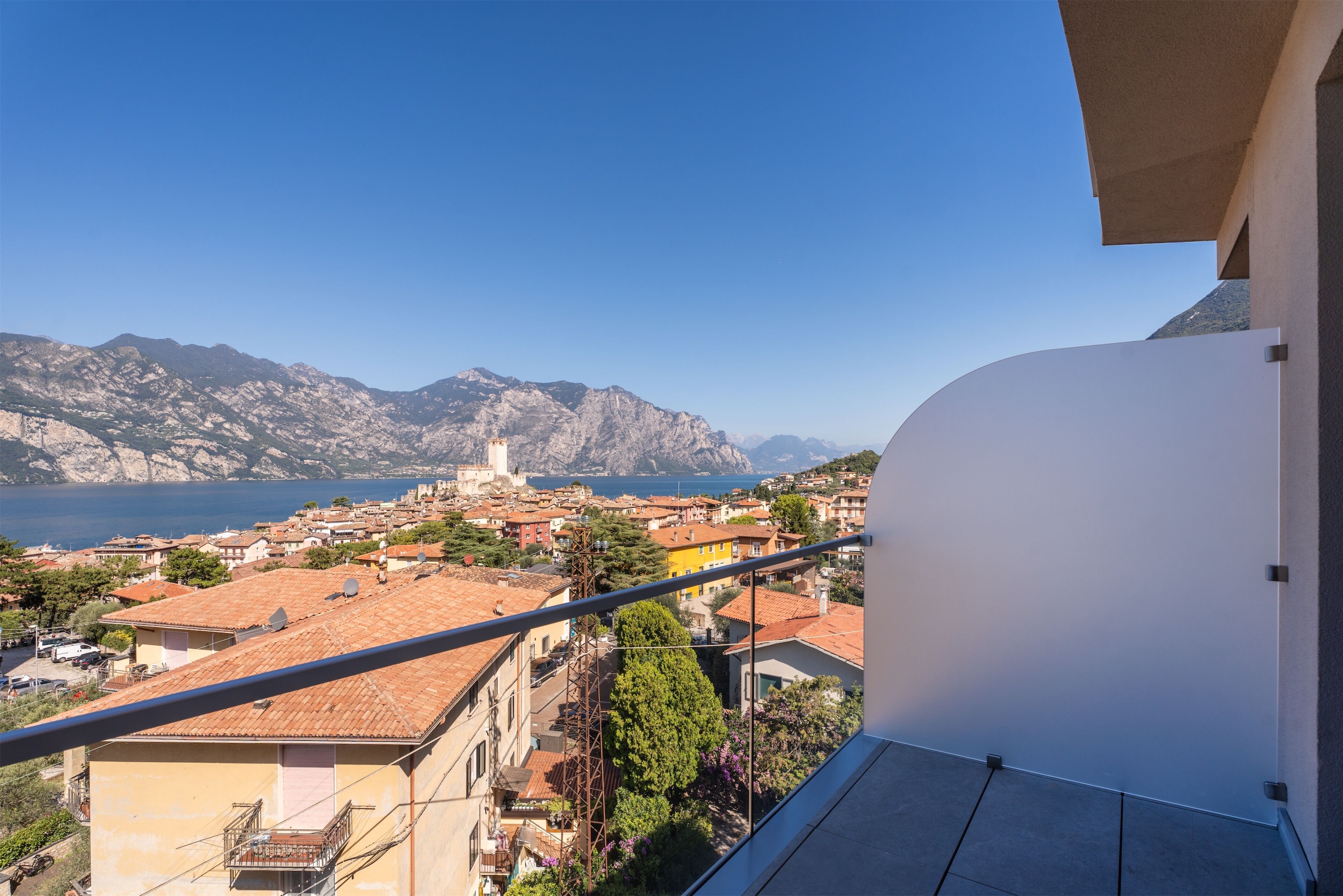 A balcony with a view of a coastal town, mountains, and a lighthouse.