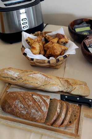 Un plan de travail de cuisine avec une miche de pain, un panier de viennoiseries et un grille-pain.