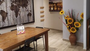 A dining area with a wooden table, black chairs, a world map artwork, a framed picture of a bridge, and a vase with sunflowers. - New Paradise (Rome)