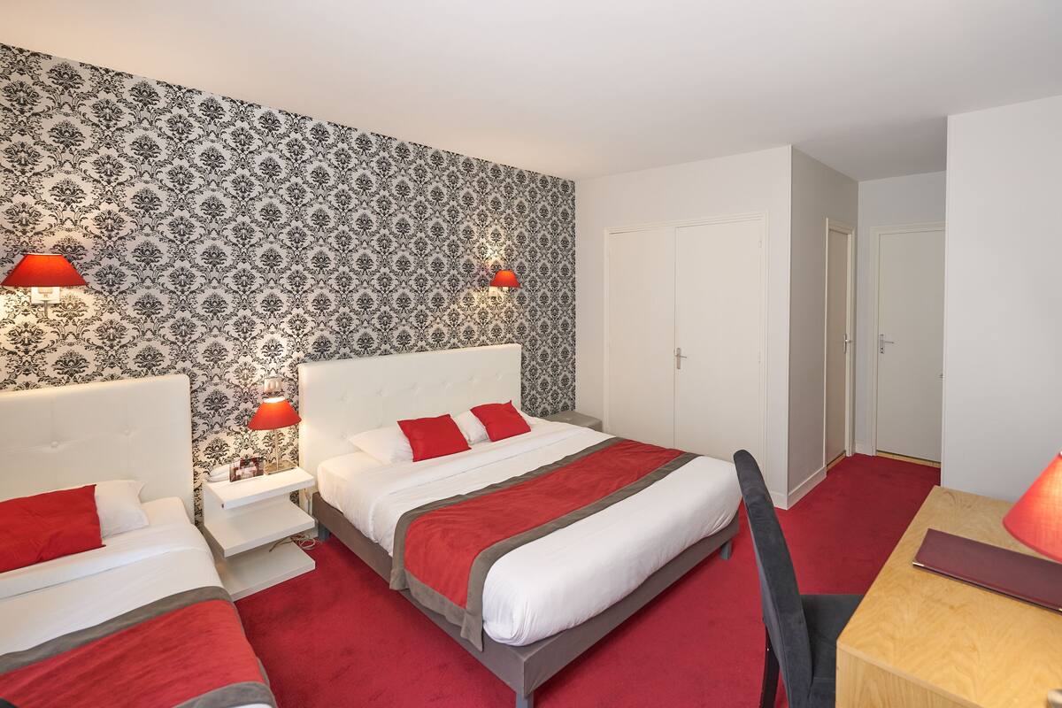 A hotel room with a large bed, two bedside tables, a desk, and a TV.