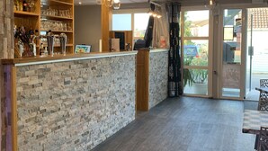 A bar area with a brick wall, wooden shelves with glasses, and a counter. - Fasthôtel Orléans Sud Zénith (Orléans)
