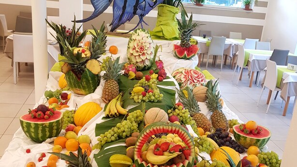 A fruit display with various fruits and a decorative fish sculpture. - Hotel Helvetia (Lignano Sabbiadoro)