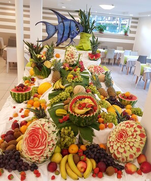 A fruit display with various fruits and a decorative fish sculpture. - Hotel Helvetia (Lignano Sabbiadoro)