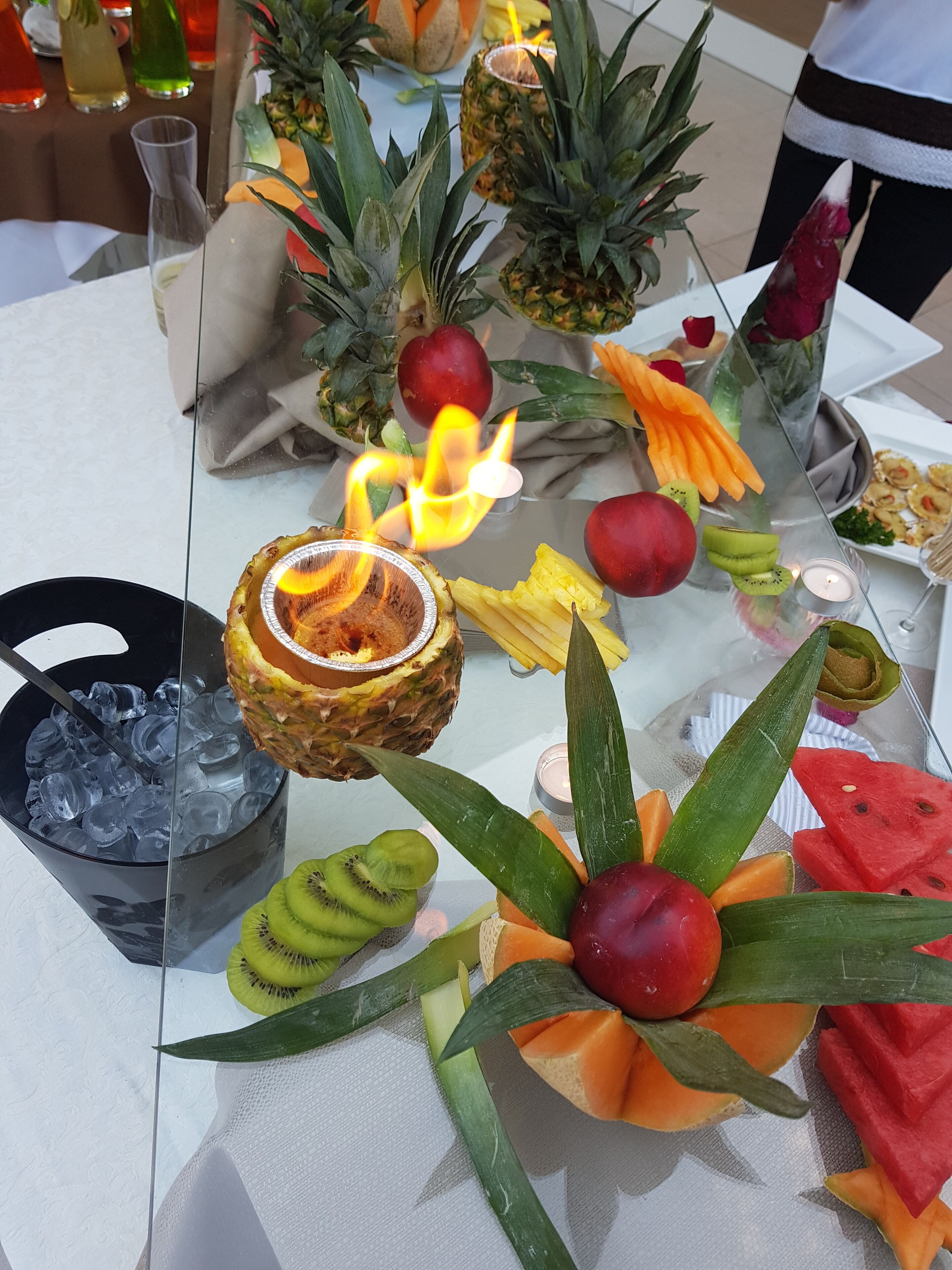 Una mesa con diversas frutas y una bebida con una vela encendida.