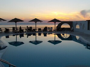 Een buitenzwembad, parasols bij het zwembad en ligstoelen