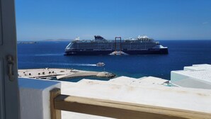 A large cruise ship docked at a port with clear blue skies and calm waters. - Gorgona Hotel (Mykonos)