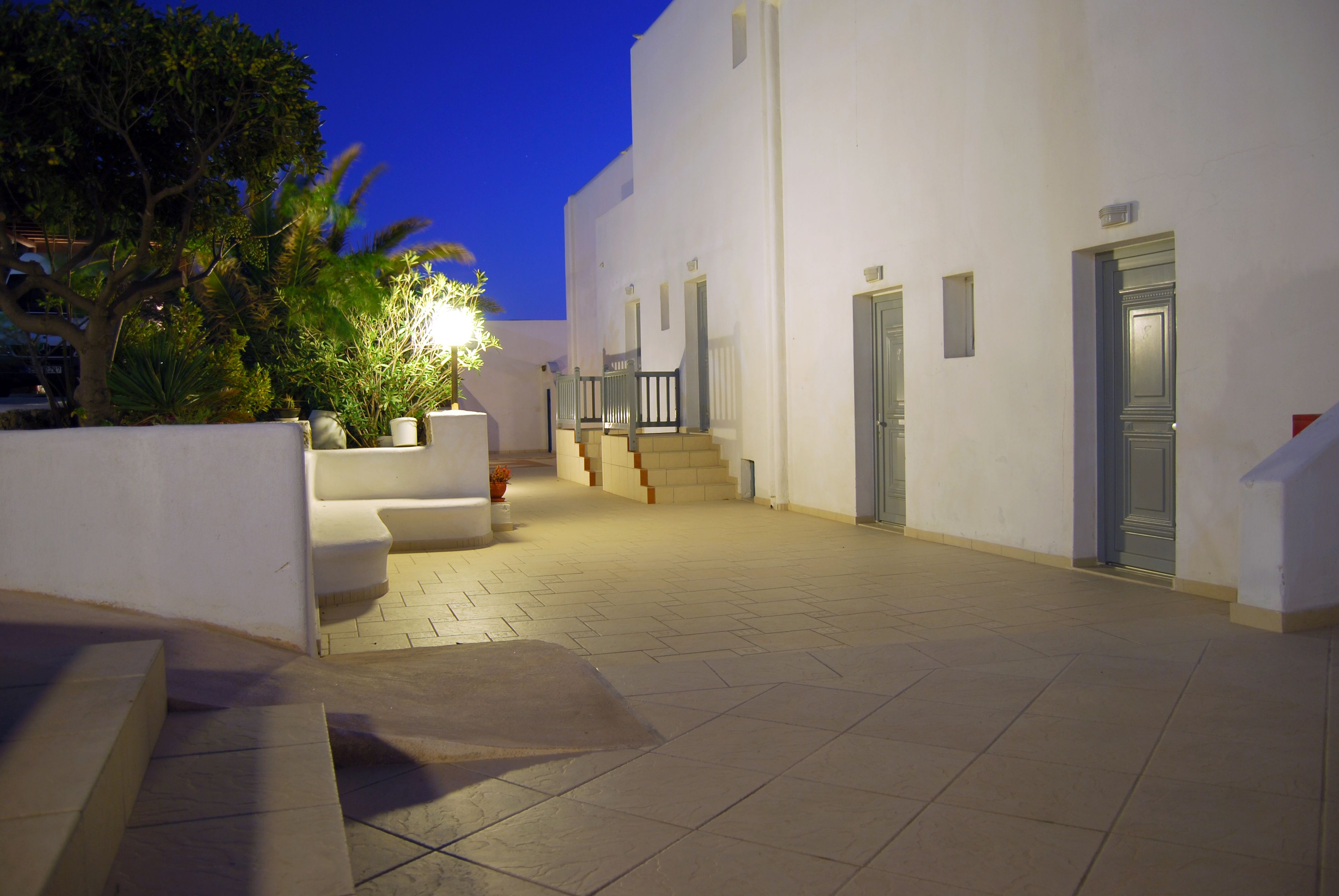 A courtyard with a white building, steps, and a tree.