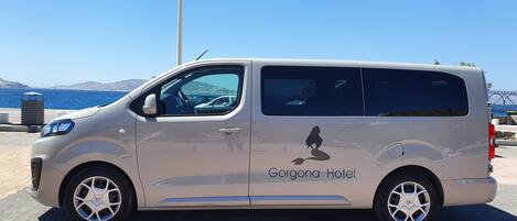 A white van parked by the seaside with the text "Gorgona Hotel" on its side.