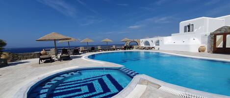 Een buitenzwembad, parasols bij het zwembad en ligstoelen