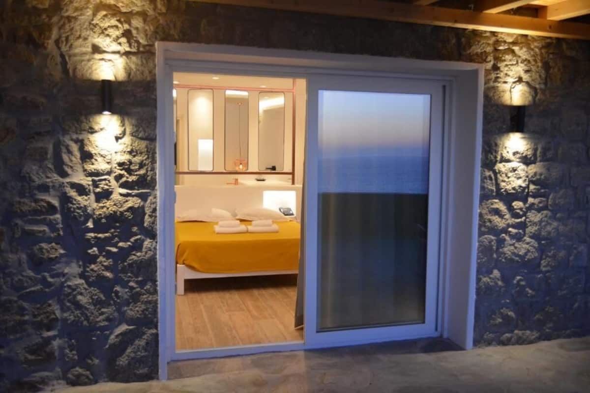 A room with a bed, a nightstand, a mirror, and a sliding door.