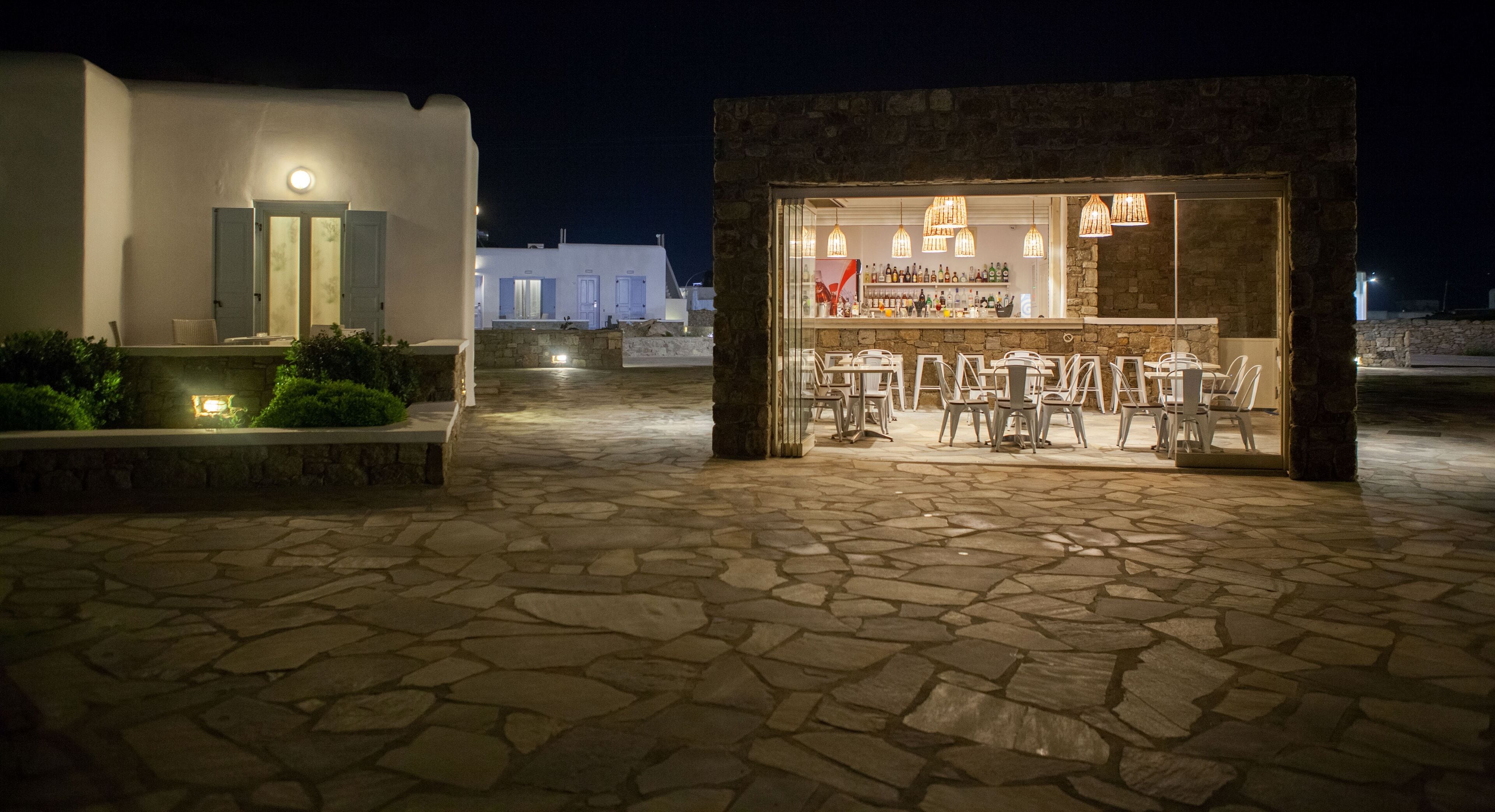 A stone-floored outdoor area with a bar and seating.