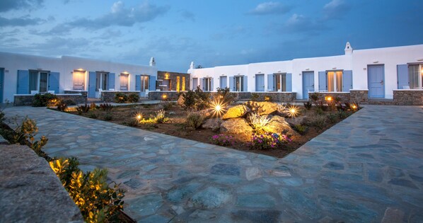 Un patio con suelo de piedra y edificios blancos con puertas azules.