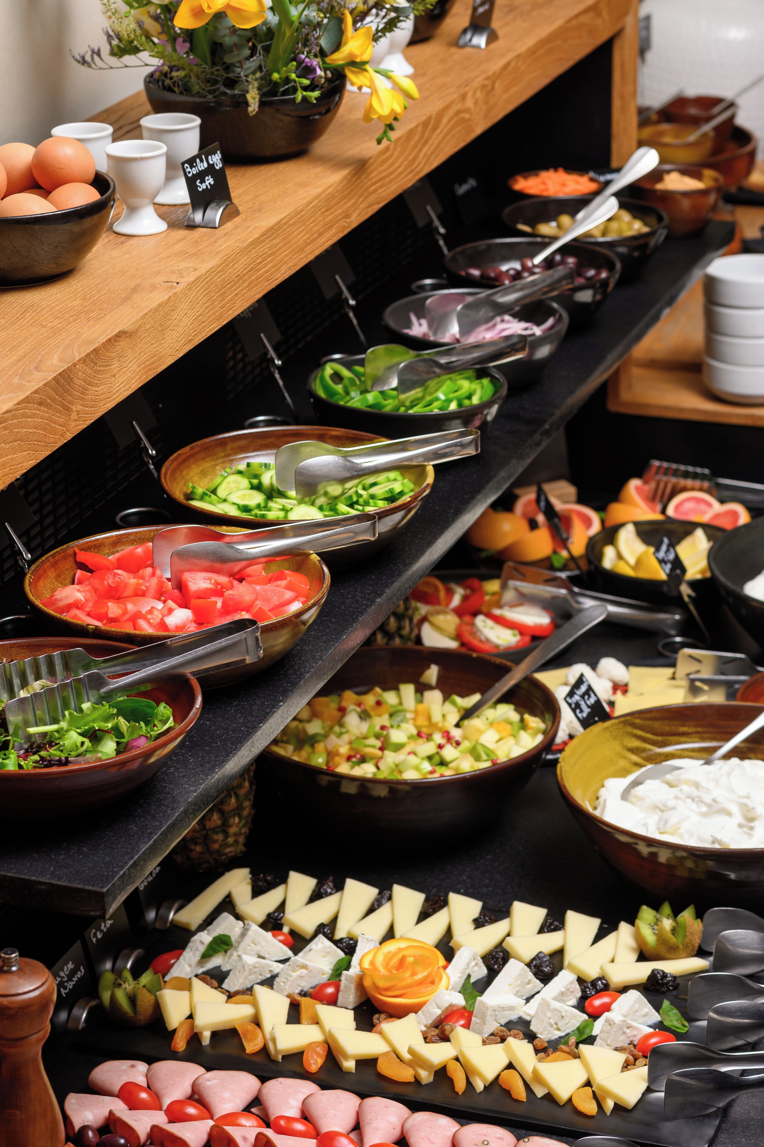 A buffet with various food items including fruits, cheeses, and meats.