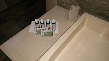 A bathroom with a bathtub, a towel, and four bottles of Korres soap.