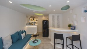 Un espace de vie compact comprenant un canapé, une petite table ronde, un coin cuisine et un bar.