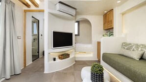 Un salon moderne doté d’un téléviseur à écran plat, d’un canapé, d’une table basse agrémentée d’une plante et d’un banc intégré.